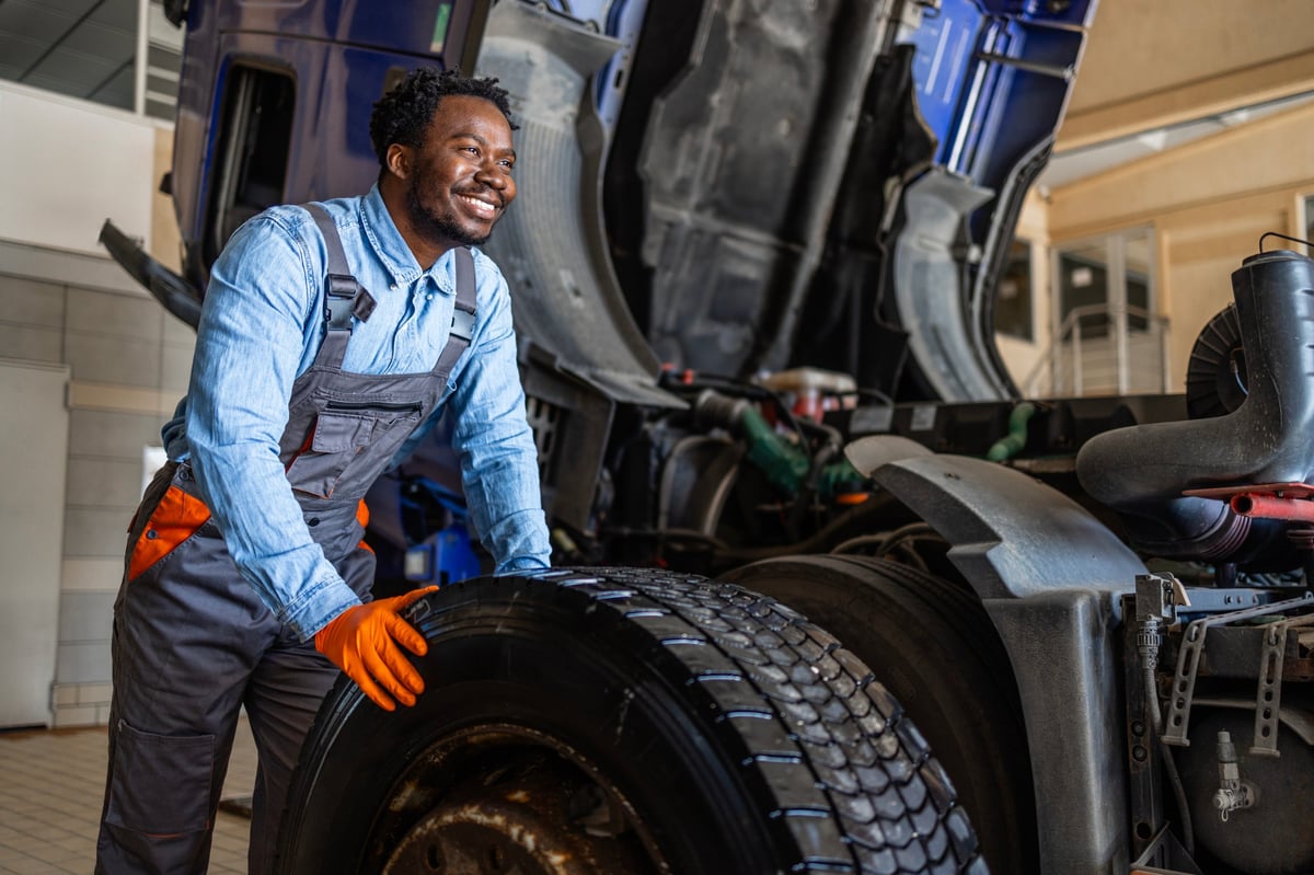 Mechanic replacing truck wheel and repairing flat tire.